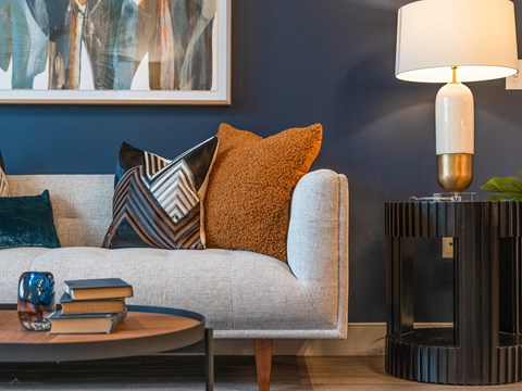 a living room with a couch and pillows and a lamp